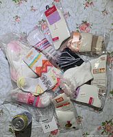 Photo showing a variety of new girl socks with diverse styles including ribbon, lace, and colorful patterns, some in packaging.