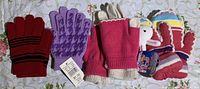 Four pairs of girls' winter gloves displayed on a floral surface, showing various colors and patterns.