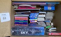 Top-down view of a box containing spiral-bound books, multiple decks of flashcards, educational posters, and sticker sheets packed together.