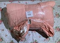 Quilt folded and wrapped in plastic showing size and condition.
