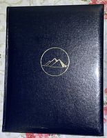 Front cover of the dark blue National Geographic Mysteries of History book showing a gold embossed mountain logo.