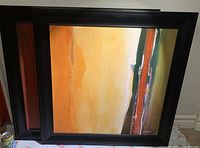 Pair of signed framed paintings showing abstract landscape scenes with dominant orange, yellow, red, and green colors framed in black wooden frames
