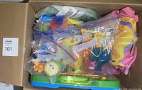 Box filled with assorted small toys in resealable bags and some loose items