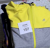 Stacked women's clothing items with Adidas hooded jacket on top, showing brand logo and color details