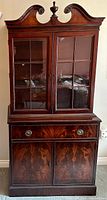 Front view of antique mahogany china cabinet with two glass doors, drawer, and lower doors