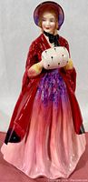 Front view of the Lady Christine bone china figurine by Paragon, showing the detailed hand-painting, red shawl, bonnet, and white muff with black spots.