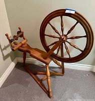 Full view of the antique pine spinning wheel showing the large wheel, supporting legs, and flyer assembly.