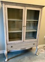 Full front view of the whitewash display cabinet showing two glass doors, bottom drawer and French style legs.