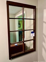 Front view of antique window pane mirror with 8 separate mirror sections within a brown wooden frame.