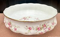 Photo of white bone china serving bowl with pink Victoriana rose floral pattern and gold rim, showing textured rounded sides and scalloped edge.