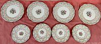 Top view of two sets of 4 plates arranged in rows showing decorative floral and ruffled border patterns.