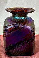 Front angled view of square iridescent purple art glass vase with swirling patterns and flared rim.