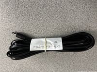 Coiled black DC power extension cable with male barrel connector visible, label indicating length