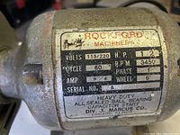 Close-up of Rockford Machinery motor rating plate showing power rating 1/2 HP, voltage 115/220, 3450 RPM, model specifications.