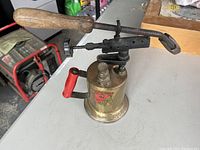 Front and side view of the antique brass soldering iron with red handle and label.