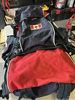 Front view of the backpack showing black and red fabric with a Canadian flag patch sewn on the front compartment.