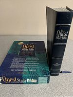 Photo showing The Quest Study Bible in its original boxed packaging with descriptive text and the hardcover spine of the Bible itself.