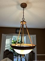 Photo of ornate three-bulb ceiling light fixture mounted on ceiling, showing hanging frosted glass bowl and bronze/gold decorative metal frame.