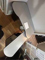 Overhead view of L-shaped desk with light grey laminate finish, showing the joined desk surfaces positioned against two walls.