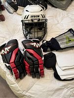 Full view of helmet, gloves, and shin pads on bed surface