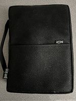 Closed black leather zippered case with a handle and a white fish symbol attached to it.