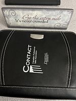 Decorative office sign with 'Go the extra mile... It's never crowded.' inscription on a distressed gray background with swirl designs.