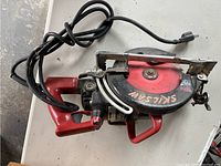 Top view of the circular saw showing the red handle, black blade housing with SKILSAW printed, and coiled power cord.
