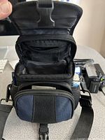 Open black padded carrying case showing several compartments and mesh storage.