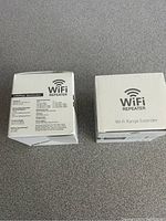 Two boxed WiFi range extenders in unopened original packaging, one with specs visible
