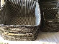 Close-up photo of two brown-coloured baskets with black and white striped fabric lining, rectangular shape, woven material.