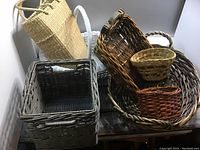Photo showing seven woven baskets in various sizes and colors arranged closely together on a wooden surface