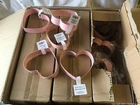 Box containing six pink heart-shaped cookie cutters with labels showing brand and care instructions