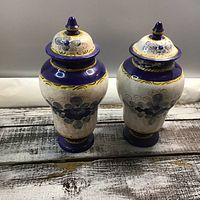 Pair of Deruta hand painted ceramic vases with lids, blue, white and yellow floral design, glossy finish.