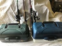 Two Flambeau tackle boxes with fishing rods and reels behind