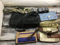 Photo showing seven items: Derek Alexander black leather purse, Liz Claiborne patchwork leather purse, blue change purse with leaf cutout pattern, tan and royal blue change purse, and three belts in metallic gold braided, metallic gold with buckle, and black with buckle.