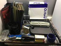 Full lot shot showing paper cutter, paper ream, file folders, desk organizers, staplers and other office supplies arranged on a shelf