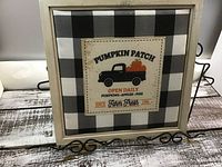 Front view of black and white buffalo check framed wall hanger with fabric print showing vintage truck with pumpkins and text 'Pumpkin Patch Open Daily'