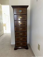 Full view of the Columbia 7 drawer lingerie armoire showing its height, dark wood finish, and brass drawer handles.