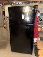 Front view of black Kenmore refrigerator freezer unit in basement.