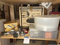 Wide-angle view showing large white vintage Tupperware containers, boxed Westbend wok, and pasta maker box with metal cutters in front.