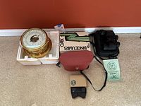 Ships weather gauge and three sets of binoculars arranged side-by-side on carpet.