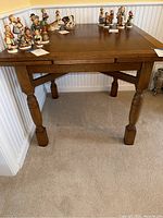 Full view of wooden square table showing detailed carved legs and a flat wooden surface. Table is medium brown in color and has classic styling.
