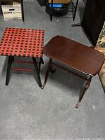 Photo showing both side tables on concrete floor: rectangular dark wood table on right, square woven strap stool on left