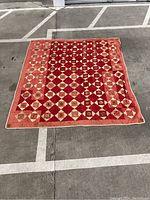 Full view of the antique red quilt blanket laid flat showing overall geometric pattern and border.