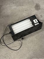 Full top view of the Daavlin lamp light showing the black housing and rows of fluorescent tubes with attached power cord.