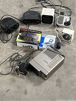 Lot showing multiple clocks, a boxed Time Master clock, Sony mini TV, and a Panasonic phone. Various cords and accessories included.