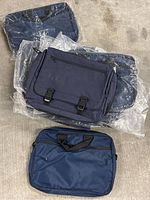 Lot of 12 navy blue computer bags, including messenger bags and zippered sleeves, some still packaged in plastic