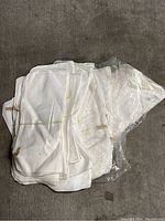 Stack of white cloth napkins folded and some wrapped in plastic on a dark surface.