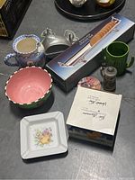 Miscellaneous kitchen items arranged together showing ceramics, boxed crackers, mugs, salt and pepper shaker, metal nutcracker, and other items.