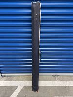 Full view of the vintage Radiant projector screen in its black fabric carrying case, showing the entire length and handle for portability